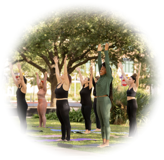 A circular photo of a group of women yogis doing yoga on the lawn of the MVP studio