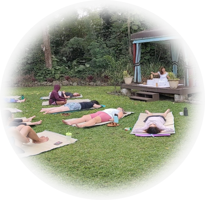 A group of yogis laying on the grass in yoga mats.